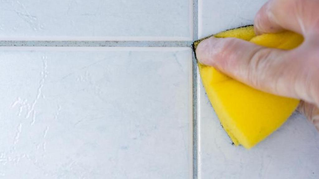 Limpieza de moho en las juntas del baño con esponja.