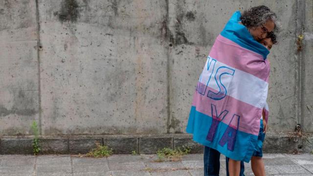María José Rodríguez abraza a su hijo, Alejandro, envueltos en la bandera trans.