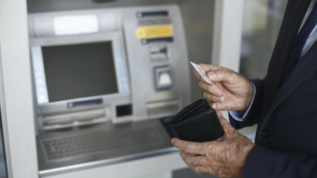 Imagen de archivo de un jubilado sacando dinero.