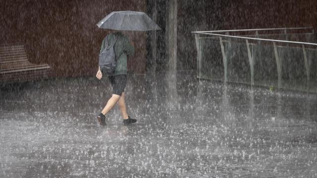 Una mujer se protege de lluvias torrenciales.
