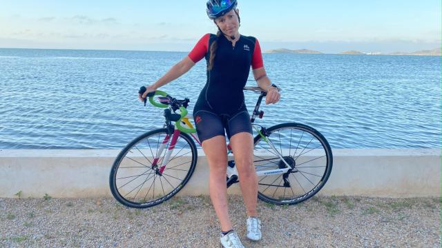 Cecilia Sopeña, posando con su bicicleta en una playa del Mar Menor.