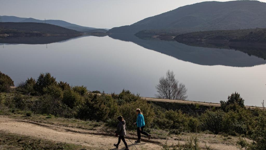 Dos personas haciendo senderismo a orillas del embalse de El Atazar.