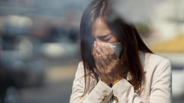 Una mujer se tapa con un pañuelo de papel ante un estornudo.
