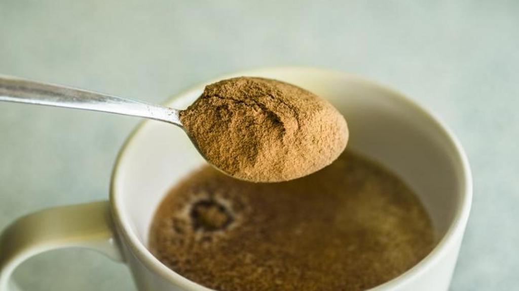Cucharada de canela sobre una taza de café.