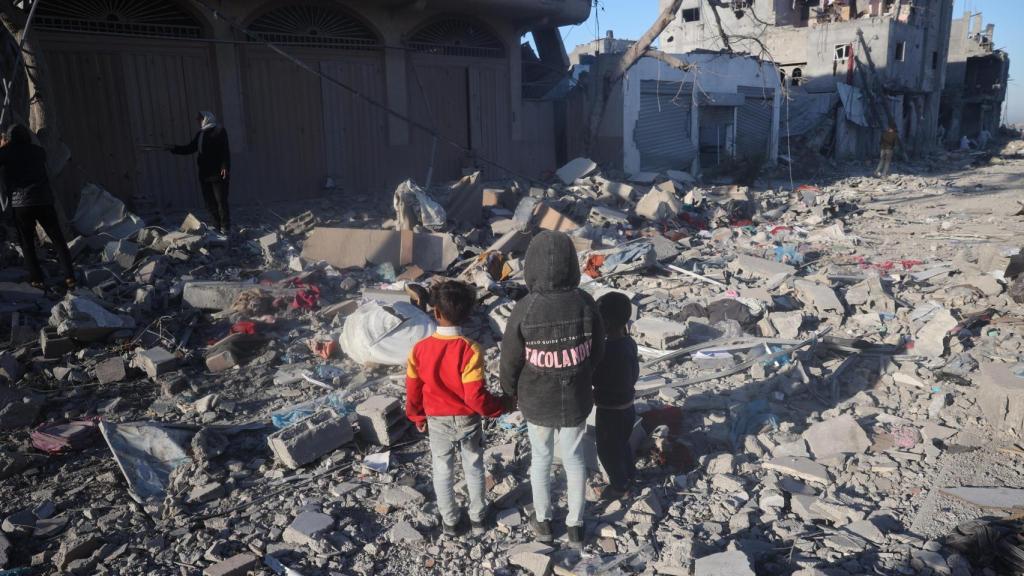 Niños gazatíes observan los escombros de lo que antes era su casa en Rafah.