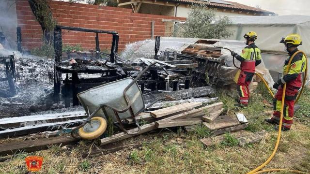 Dos bomberos junto a varios enseres calcinados en una vivienda de La Puebla de Almoradiel.