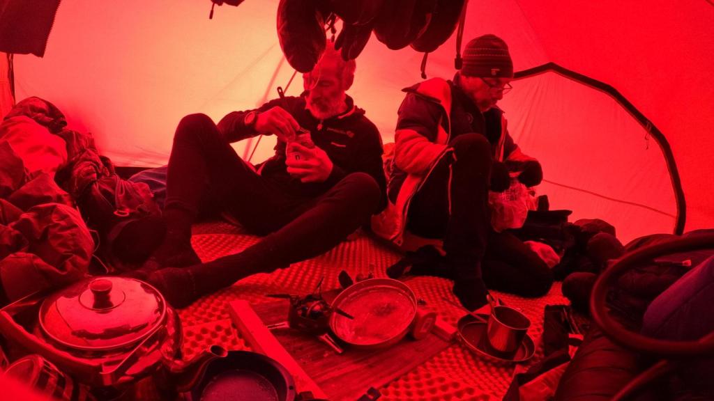 Los tres exploradores descansan y comen en el interior de una tienda de campaña, durante la travesía 'Mar de Hielo 2025'.