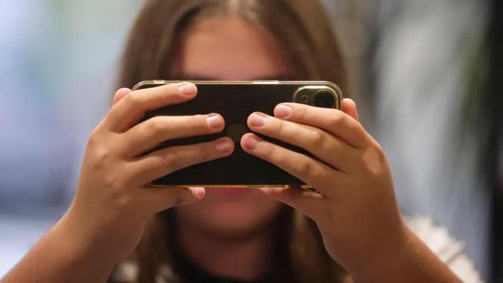 Una adolescente consulta su teléfono móvil.