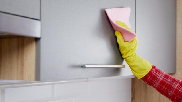 Una persona limpiando los muebles de la cocina
