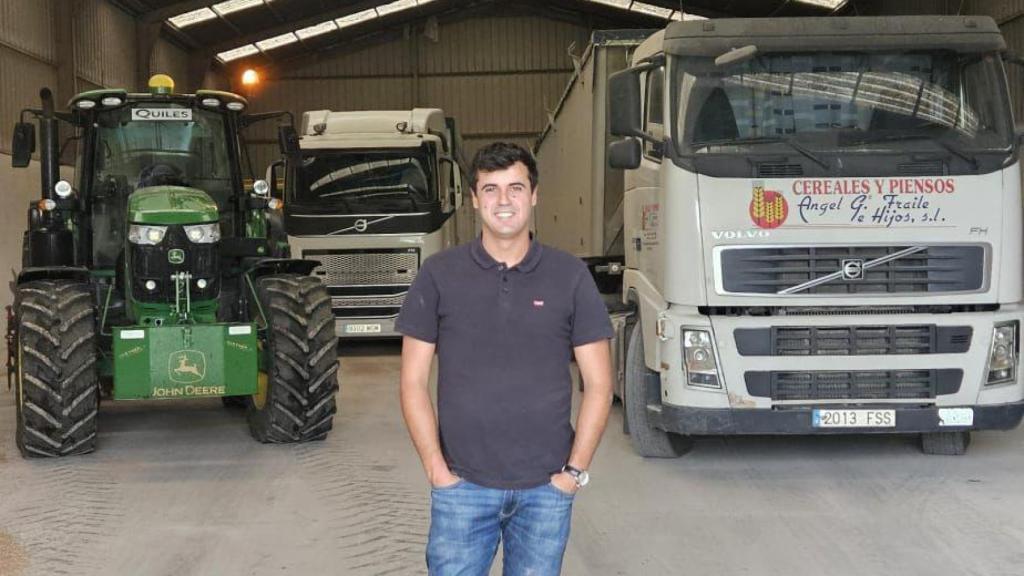 Álvaro García junto con el tractor y la empresa de camiones de su familia.