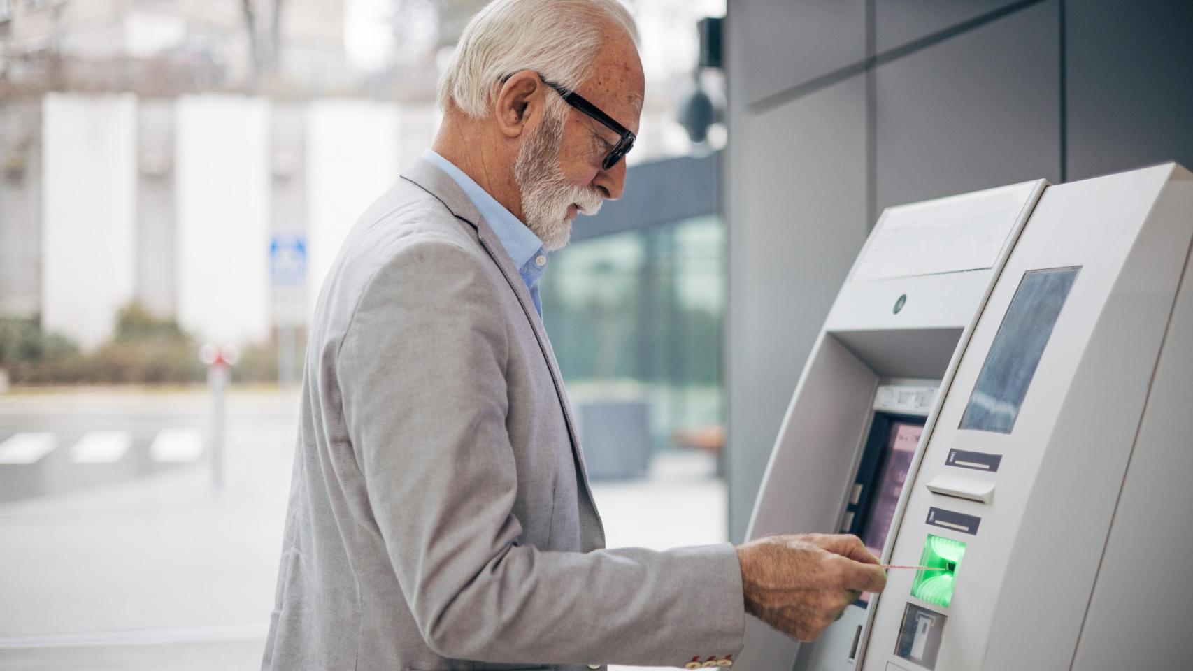Un jubilado retira efectivo en un cajero automático.