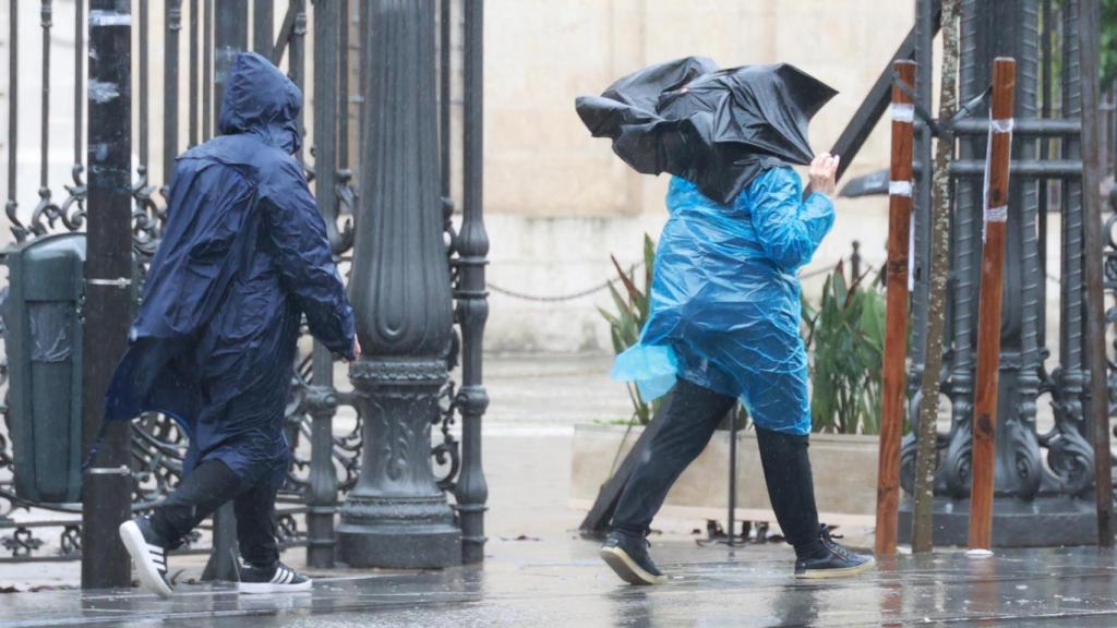 Dos personas se protegen de la lluvia en Sevilla.