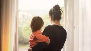 Imagen de archivo de una madre y su hija mirando por la ventana.