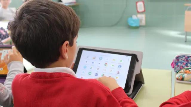 Niño hace uso de una tablet en clase.