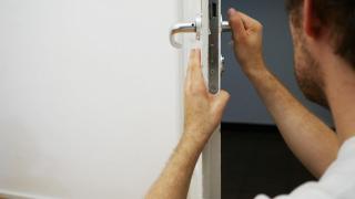 Un cerrajero arregla la cerradura de la puerta de una casa robada.