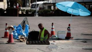 Imagen de archivo de un trabajador protegiéndose del sol con una sombrilla en Valencia.