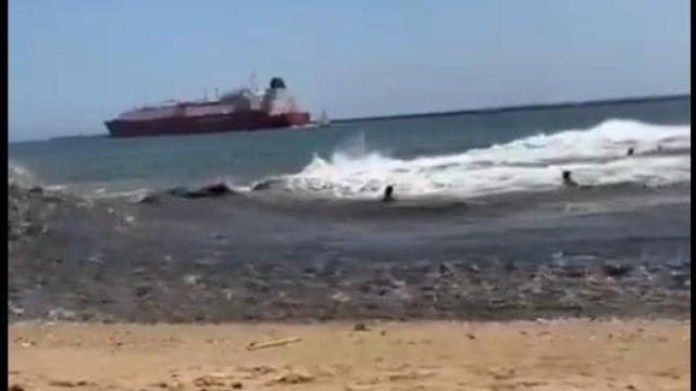 Momento en el que una ola provocada por el paso de un barco hiere a varios bañistas en una playa de Huelva