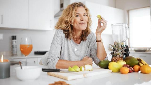 Mujer comiendo en la encimera de la cocina.