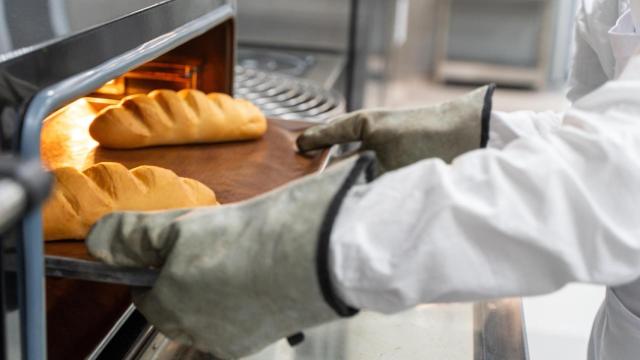 Un panadero saca una bandeja con pan recién horneado
