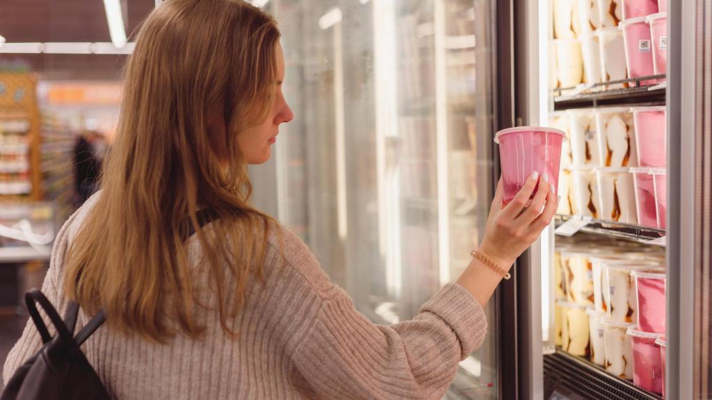 Una persona cogiendo un helado del congelador de un supermercado