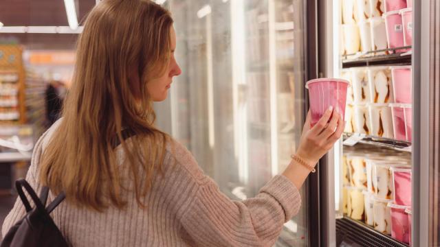 Una persona cogiendo un helado del congelador de un supermercado