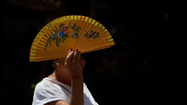 Una mujer se tapa el sol con un abanico.