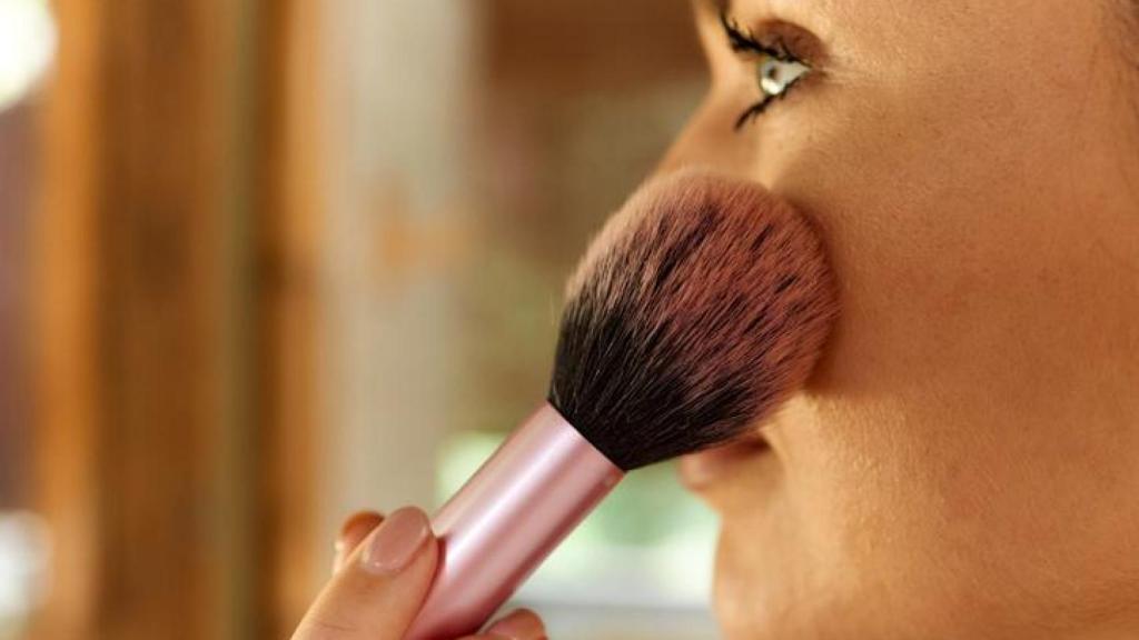 Mujer aplicándose colorete.