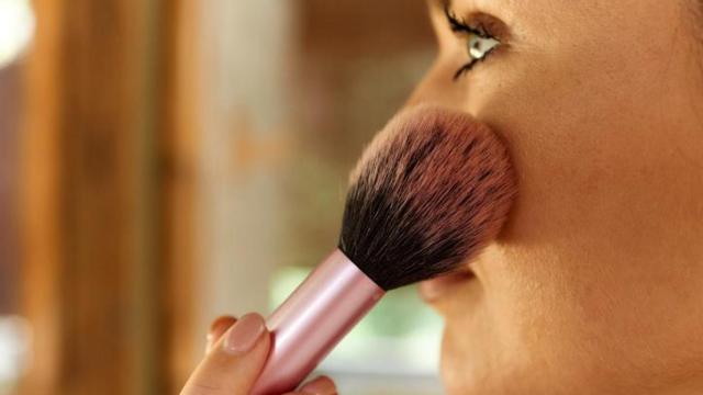 Mujer aplicándose colorete.