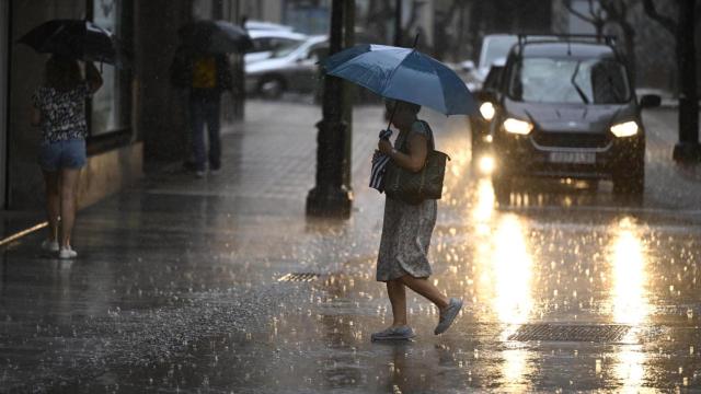 Una mujer cruza, este miércoles una calle de la ciudad de Castellón bajo una intensa lluvia.