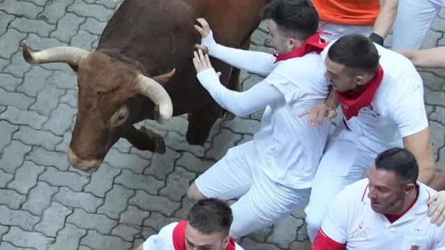 Un mozo tropieza ante uno de los toros de la ganadería Jandilla durante el quinto encierro de los Sanfermines.