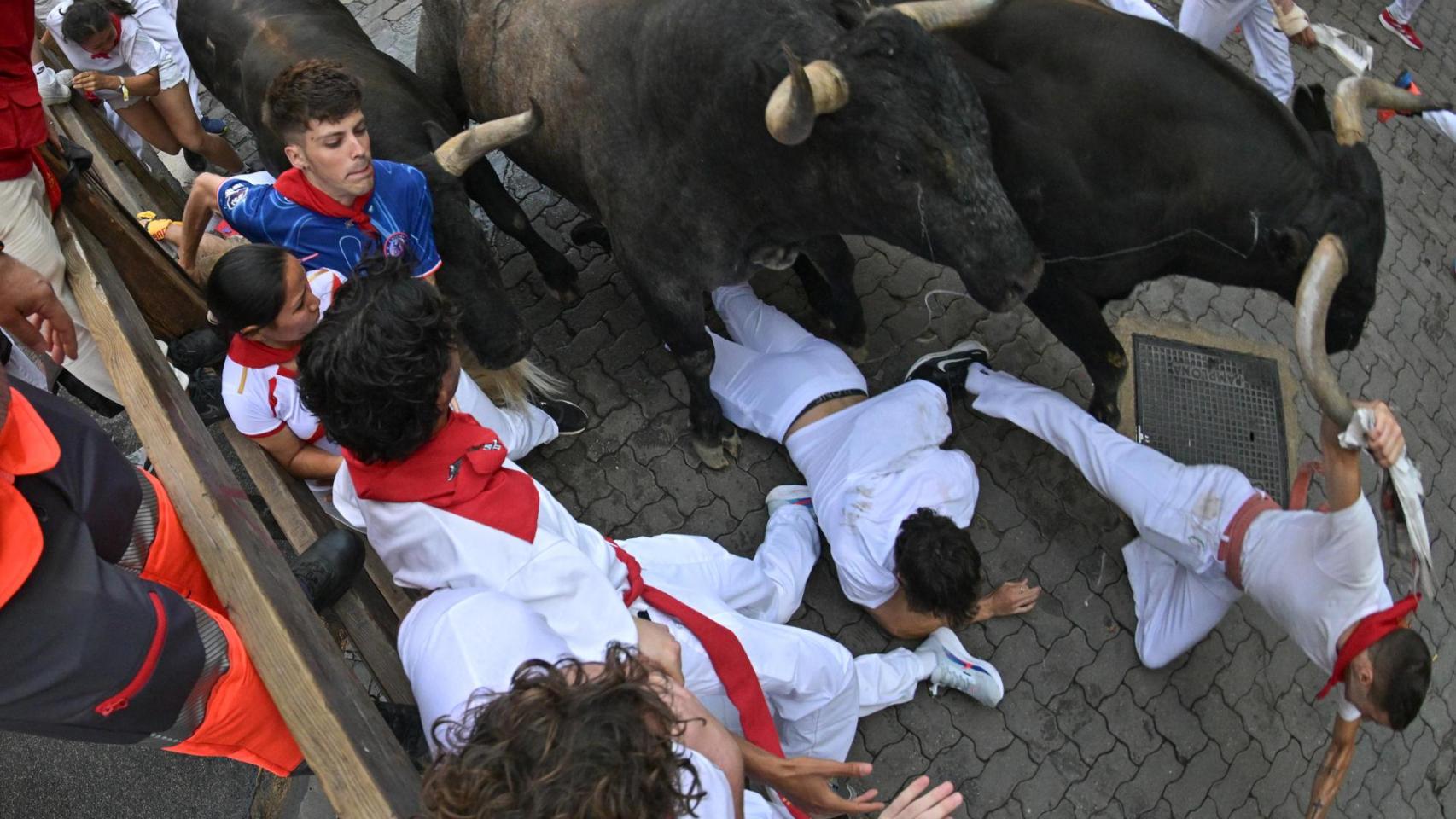 Dos mozos caen al paso de los Miura durante el octavo y último encierro de los Sanfermines.