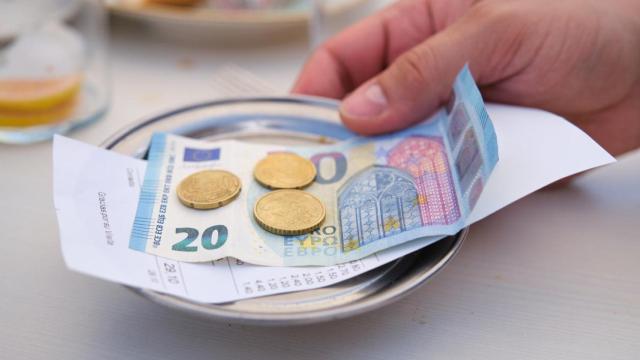 Bandeja de metal con un billete y monedas del cambio.