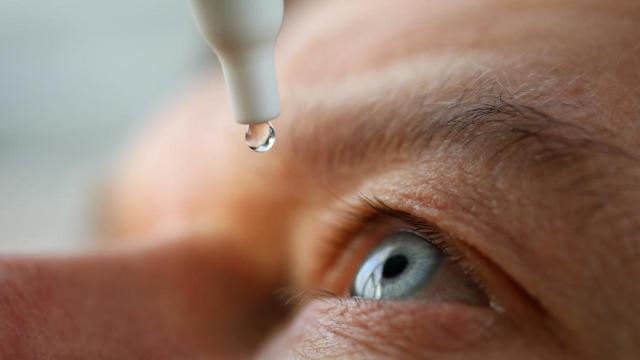 Una persona echándose gotas en los ojos.