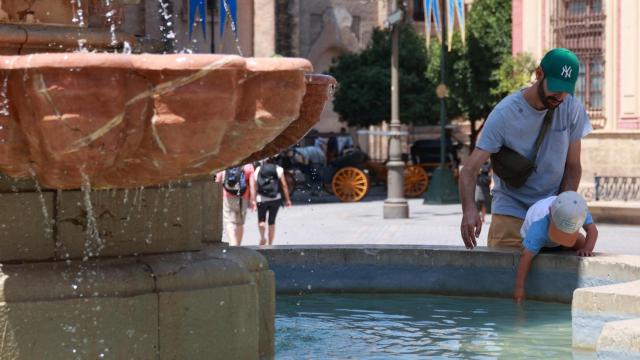 Imagen de un hombre y un bebé en una fuente de Sevilla.