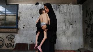 Una madre desplazada sostiene a su hijo en la ciudad de Gaza.