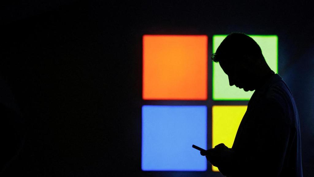 Un hombre mira su teléfono delante del stand de Microsoft en el MWC de Barcelona.