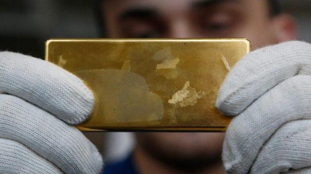 Una persona sujeta un lingote de oro.