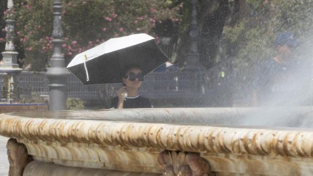 Una joven se refresca junto a una fuente.